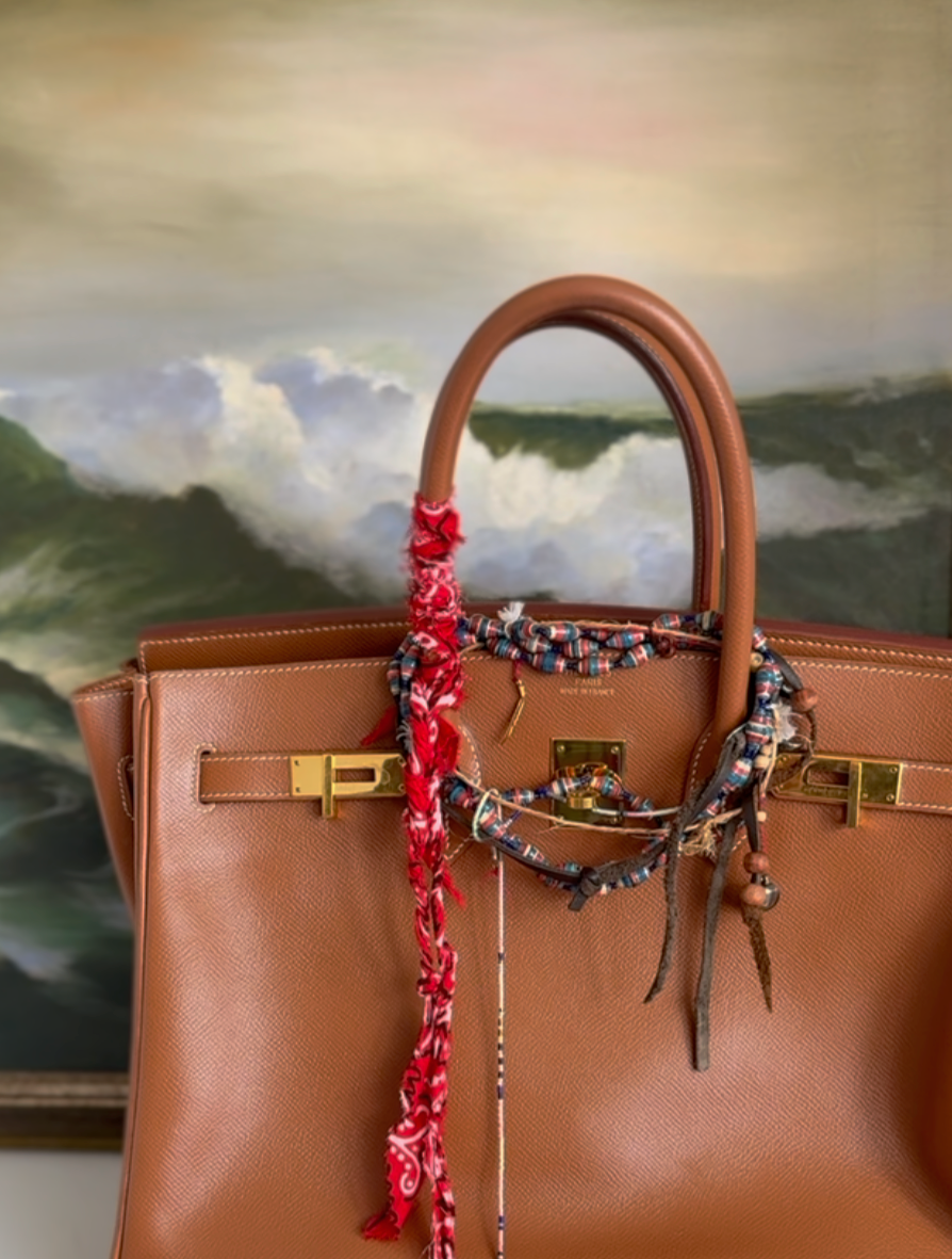 Tan leather top-handle bag styled with knotted bandana scarves and charms